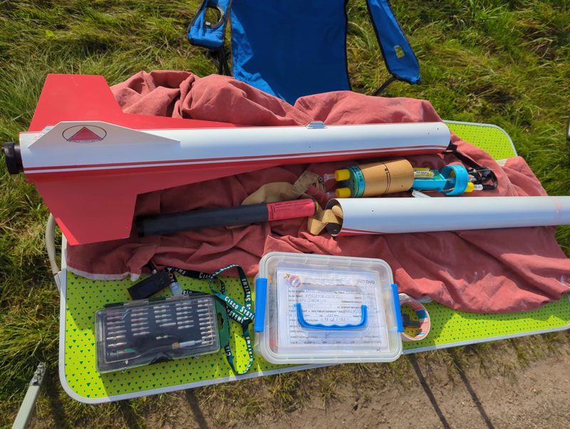 Flight prep table with the rocket sections, avionics bay, motor and flight card